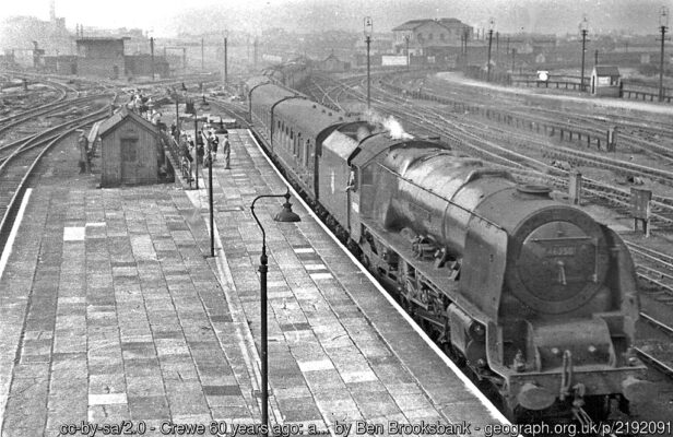 View northward from the footbridge at the north end; ex-London & North Western West Coast Main line. The 10.05 Glasgow Central to Birmingham New Street, headed by Stanier 'Coronation' 8P 4-6-2 No. 46250 'City of Lichfield', is coming into Platform 4 across Crewe North Junction (see large signalbox, left background). On the right, the Manchester lines curve in past the Up Carriage Sidings and the Horse Dock; the lines on the left lead to Platforms 5 and 6. Over to the left are the lines to Chester.